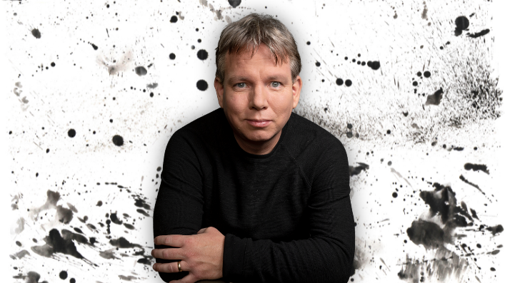 LMU professor of physics Jonas Mureika with a splatter black paint background